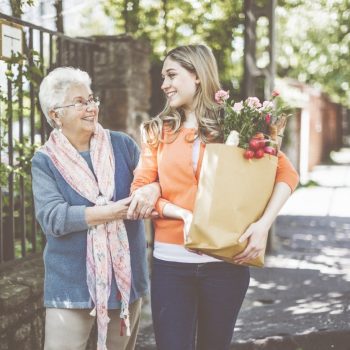 Smiling granddaughter is helping her grandmother to carry home the packages after shopping